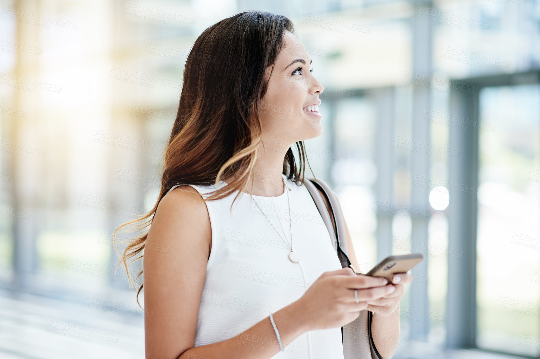 Buy stock photo Phone, text message and thinking with business woman in lobby of workplace for social media. App, communication and smile with employee in corridor or foyer of office for feedback or online chat
