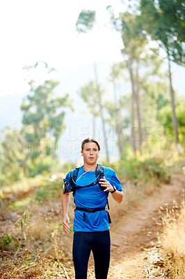 Buy stock photo Fitness, man and running in nature for training, cardio exercise or challenge with music. Runner, earphones or workout on forest trail with motivational podcast, wellness or intense breathing on path