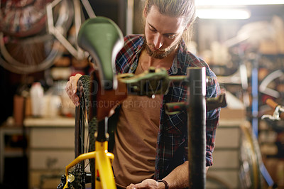 Buy stock photo Fixing, bicycle and man in workshop, serious and inspection of damage in small business and service. Repair, wheel and person with bike, entrepreneur or maintenance of vehicle, technician or shop