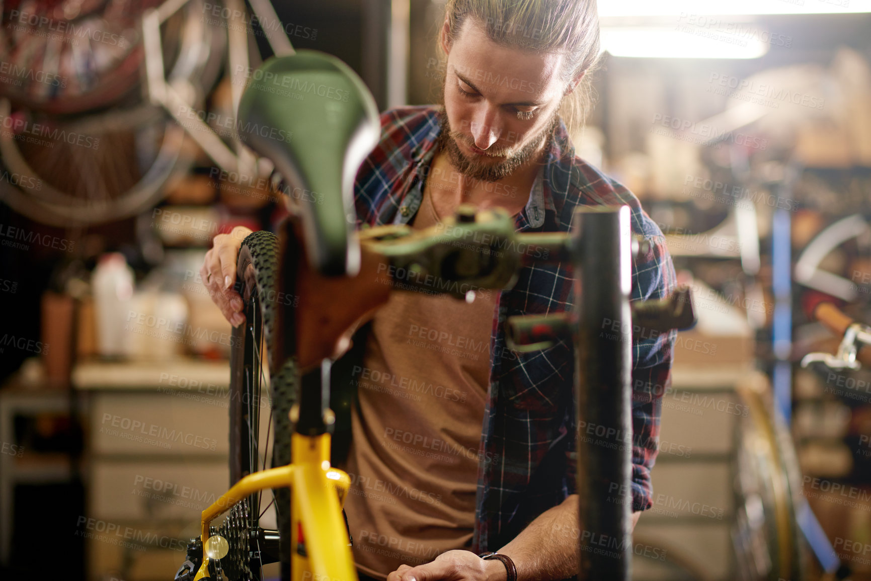 Buy stock photo Fixing, bicycle and man in workshop, serious and inspection of damage in small business and service. Repair, wheel and person with bike, entrepreneur or maintenance of vehicle, technician or shop