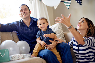 Buy stock photo Birthday, celebration and parents with toddler, home or gift for first party, mom and dad in lounge. Happy, man and woman with present for child, love and family on weekend in house or together