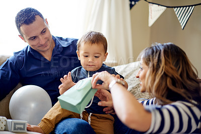 Buy stock photo Parents, toddler and giving gift at birthday party, celebration event and family tradition in lounge. People, surprise package and child milestone with present, special occasion and bonding at house 