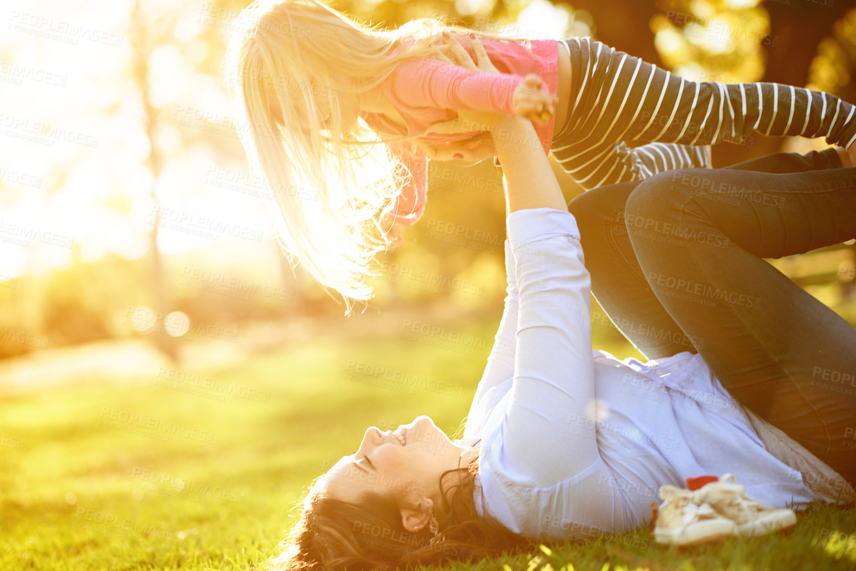 Buy stock photo Mom, girl and lift on ground at park for airplane, bonding and games with smile, flare and outdoor in nature. People, mother and daughter with fun, play and relax on grass for flight in Germany