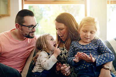 Buy stock photo Talking, home and parents on sofa, girls and bonding together with happiness in living room. Apartment, family and mother with father, kids and daughters with smile, conversation and relax with love
