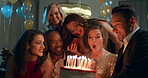 Young happy diverse friend group celebrating young caucasian blowing out candles on cake on her birthday at party