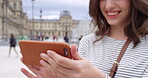 A woman smiling while using her smartphone in front of the Louvre