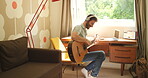 A young man singing and playing guitar at home