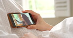 Closeup of a woman using a smartphone to make a video call in bed