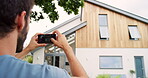 A man taking photos of his house from the outside using his smartphone