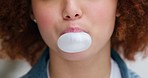 Closeup of a woman with afro hair blowing bubbles with chewing gum