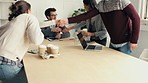 A businesswoman brings her coworkers cups of coffee. A diverse happy group of businesspeople greeting each other with handshakes and drinking tea during a meeting. Colleagues talking in a meeting