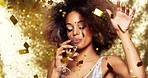 Young african american woman with an afro celebrating at a party drinking a glass of champagne and dancing. Carefree young woman dancing and drinking champagne while gold confetti falls