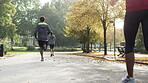 Back of a group of men and women jogging through a park together in slow motion. A group of friends doing a cardio workout and running through a garden together.A group of friends exercising together