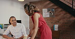 Young businesswoman walking in the office talking to a diverse group of staff members. Hispanic businesswoman in leadership position training colleagues using a computer and tablet.