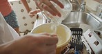 A woman pouring flour into a bowl of pancake batter while cooking breakfast