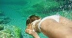 Woman in white bikini swimming underwater in clear lake. Woman on holiday swimming underwater in a lake