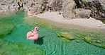 Young woman relaxing on a pink flamingo inflatable floating down a river. Woman relaxing sunbathing floating on a pink flamingo inflatable