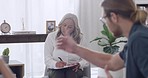 Young interracial couple arguing during a therapy session with their mature female therapist in a office while sitting on a sofa. Unhappy boyfriend and girlfriend playing the blaming game