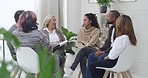 Closeup of a young diverse support group during a meeting with a professional mature female therapist. Group of employees looking serious during a team counselling session. Mental health in the workplace