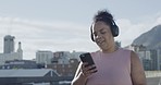 Plus size speed walker exercising, using cellphone to track weight loss in city. Chubby active mixed race woman getting fit, losing fat with routine outdoor workout. Listening to music on headphones