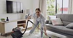 One young caucasian woman dancing while cleaning a carpet with a vacuum cleaner in a lounge at home. Cheerful and energetic woman having fun while doing chores and housework for a tidy apartment