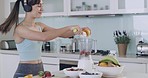One cheerful young mixed race woman dancing and singing while making healthy detox smoothie in kitchen at home. Drinking fresh fruit juice with vitamins and nutrients to cleanse and provide energy
