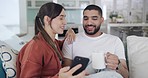 Happy mixed race couple taking selfies for special memories on cellphone while relaxing on the sofa at home. Cheerful boyfriend and girlfriend making funny silly faces while capturing photos
