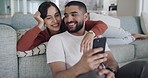 Happy and affectionate mixed race couple using a phone to text message, online chat or browse social media. In love boyfriend and girlfriend laughing while relaxing together on the sofa at home