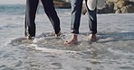 Smiling mixed race couple walking through water on beach and holding hands. Hispanic boyfriend and girlfriend bonding and enjoying free time on weekend. Loving man and woman on romantic walk and date