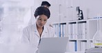 A african american scientist using a laptop in a laboratory. Female healthcare specialist working on a vaccine cure for a virus in a research lab. Expert with medical findings at a research facility