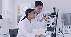 Two scientist using a computer and microscope while working on samples in a lab. Innovative biochemists making medical breakthrough and discovery in a research facility while using online technology
