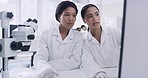 Two medical scientists discussing a virus sample, sitting inside a research facility. Specialists enter data into a computer system and analyze a cell on a petri dish to develop a cure or vaccine