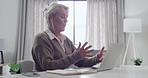 Mature woman talking during a video call on her laptop. Female psychologist working from home and giving therapy during an online consultation. Therapist using technology for session with client