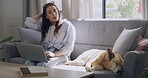 Stressed out freelance blogger petting her support dog, while remote working from home on her laptop during lockdown. Anxious woman doing research with technology and bonding with a canine companion