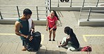 Three active people taking a break on the stairs outside. Young diverse friends relaxing and socializing at stadium after an energetic run or jog exercise. Happy male and female joggers in sportswear