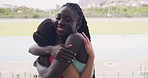 Portrait of female athletes hugging while training together at stadium. Teammates celebrating win after track and field competition. Sporty woman congratulating each other on victory at sports event