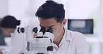 Portrait of a male scientist using a microscope at a research lab. A happy young cell biologist or biotechnology researcher working with the latest laboratory instruments in a modern science facility