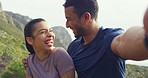 Portrait of couple laughing taking selfie at the top of a mountain with sky background copyspace. Closeup of a happy young influencer couple blogging after hiking up a mountain with rocky landscape
