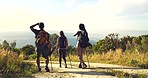 Fit and active friends hiking in nature on a mountain dust path. Friend clique on a walk in remote areas with rough terrain. Friendly male guide, and women backpacking in nature during sunset.
