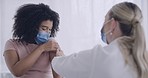 Female doctor and patient wearing masks while getting a flu or immunity booster shot at a clinic. Woman getting the thumbs up from her doctor after getting injected with the covid vaccine at hospital