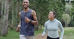 Two fit people running in a park, enjoying their daily exercise and fitness routine outdoors. Confident smiling female jogging and happy african male working out in a quiet scenic location.