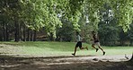 Two fit athletes running and jogging in the park or forest outdoors. Motivated and determined young man and woman maintaining speed, endurance and stamina during a cardio workout on a trail in nature