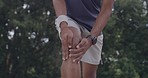 Closeup of a man with a sore knee injury from overexertion during a workout outdoors. Closeup of an uncomfortable athlete rubbing his inflamed muscles while suffering with pain and fractured joints