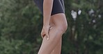 Female athlete suffering from a sports injury while standing outside. A sportswoman massaging her pulled calf muscle or leg to ease the pain after a run. Exercising comes with the risk of pain