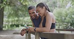 Laughing athletes using phone to take selfies for social media. Smiling man and woman feeling happy after a finished workout training exercise in nature park. Fit, athletic friends bonding in woods