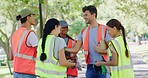 Group of community service volunteers preparing to clean a local park wearing reflector jackets for safety. Diverse happy people doing charity work and taking responsibility for the environment