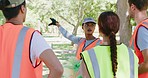 Group of diverse smiling community workers uniting for a cleanup service or project outdoors. Young happy volunteers talk before collecting trash in a park for recycling to keep nature healthy