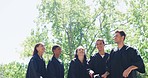 Group of graduates celebrating and throwing caps or hats into the air in tradition after university campus graduation ceremony. Smiling diverse men, women, friends graduating from college together 