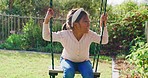 One adorable little girl playing on a swing in the backyard at home on a sunny day. A cute child having fun and smiling at a park during summer. Happy, playful and active girl enjoying her childhood