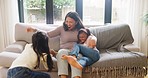 Happy family having fun on a sofa at home. Young single mother being playful while bonding with her two daughters on couch in the living room. Little girls love having their home around on a weekend